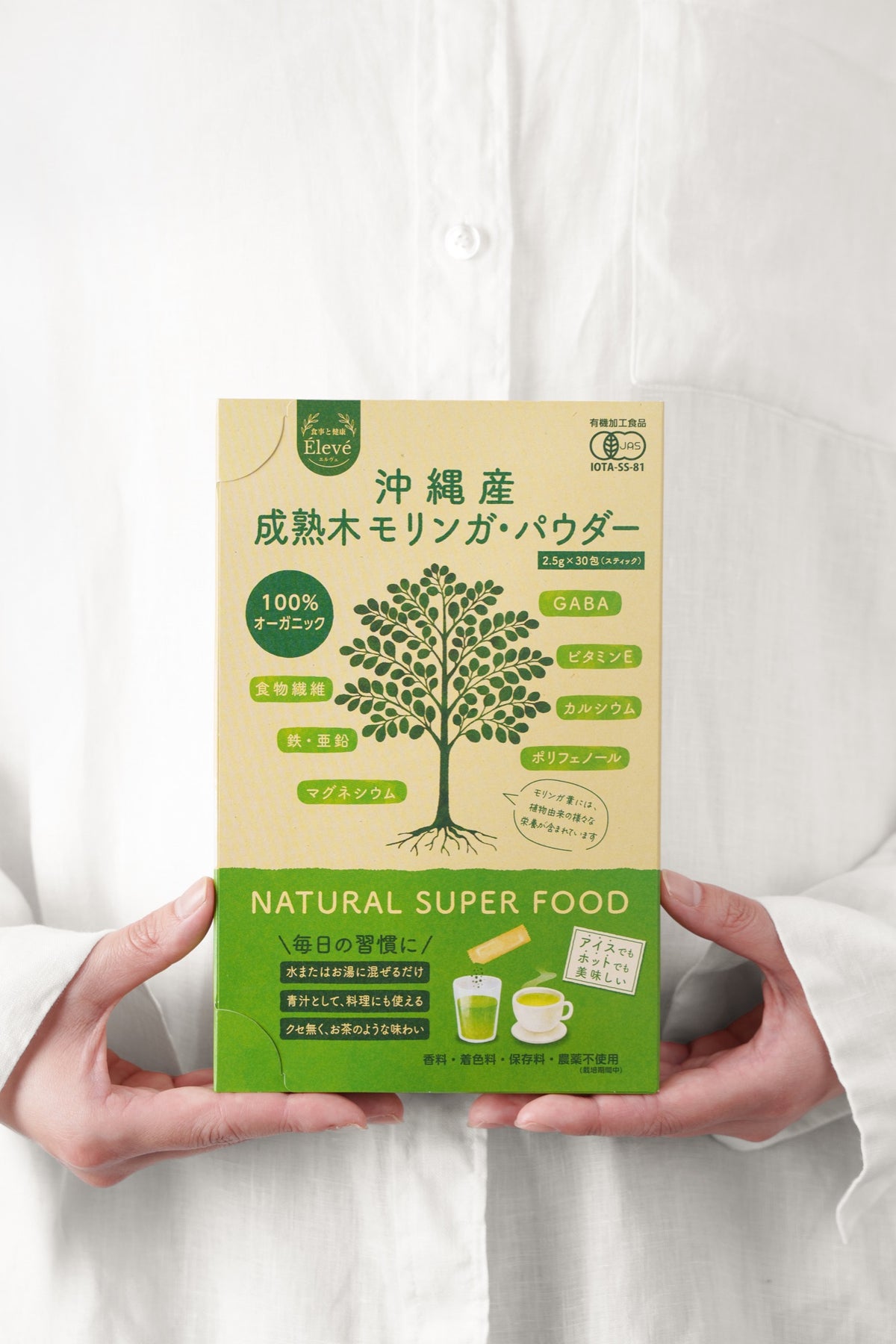 エルヴェのブランドストーリー用: ガラスポットとカップ、モリンガスティック、ドライフラワーのある落ち着いた食卓シーン